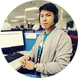 Man wearing headset sitting at a computer desk in an office.